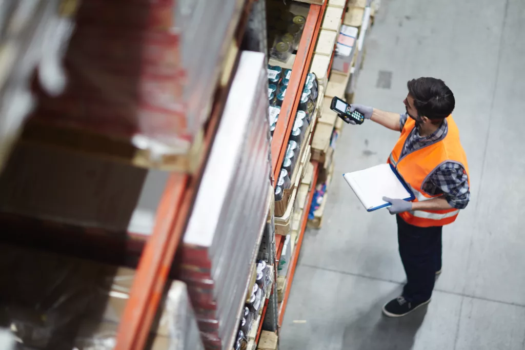 Worker with scanner making review of goods in warehouse using Sage X3 and Warehousing