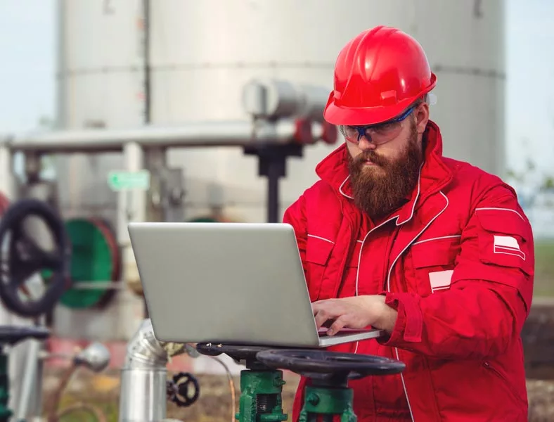 Oil and Gas engineer on laptop at oil refinery