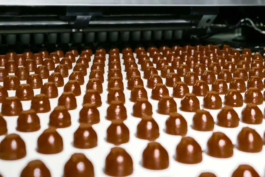 Picture or warm chocolate bonbons fresh on a conveyor belt