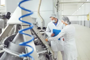 People technologists inspector in masks at food factory using a dairy management software for the inspection